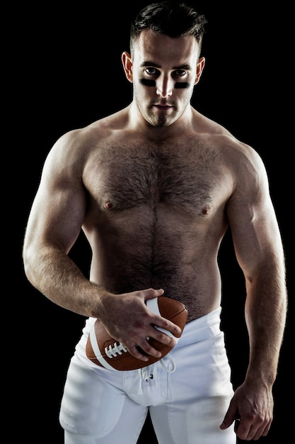 Shirtless American football player with ball