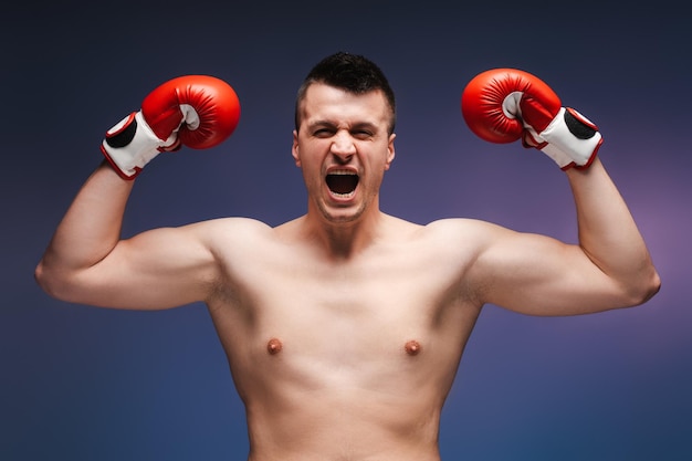 Shirtless boxer wearing red boxing gloves celebrating victory