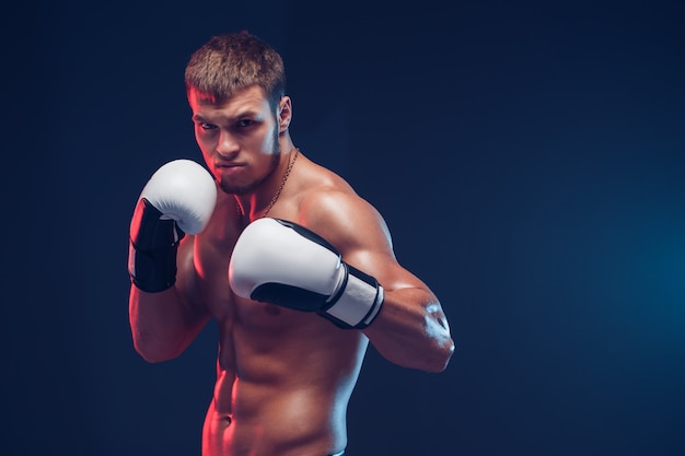 Shirtless boxer with gloves on dark background. Isolate