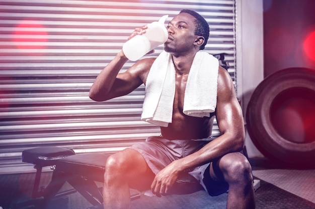 Shirtless man drinking protein shake at the crossfit gym