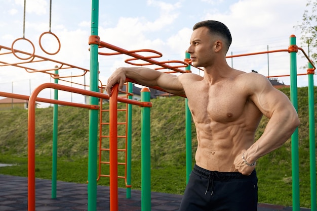 Shirtless man with muscular torso standing on sports ground