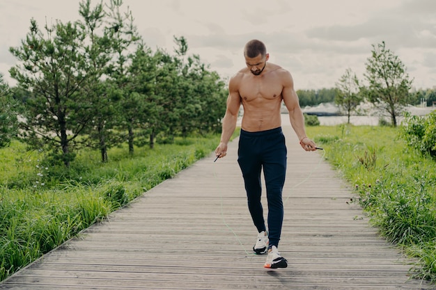 Shirtless man working out outdoors with jump rope