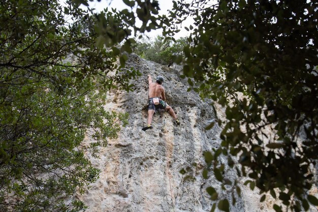 Shirtless mountaineer climbing on rock