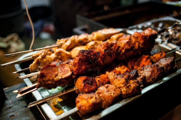 shish kebab from pork on coals at Christmas fair Roasted meat or shish kebab on metal skewers