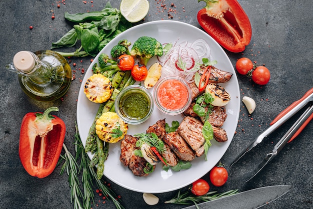 Shish kebab and vegetables grilled and served on a white plate.