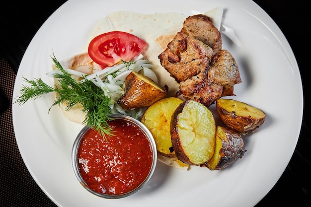 Shish kebab with grilled vegetables on a white plate