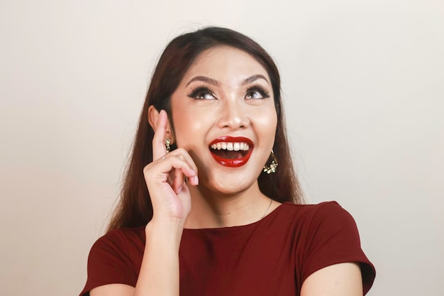 Shock face of a young Asian woman wearing a red shirt pointing upwards Advertisement concept