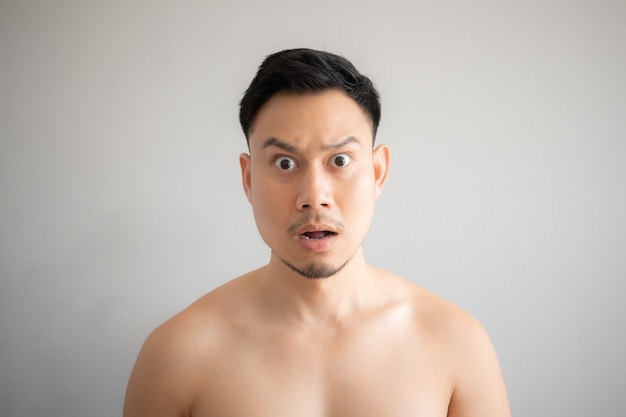 Shock and surprise face of Asian man in topless portrait isolated on gray background