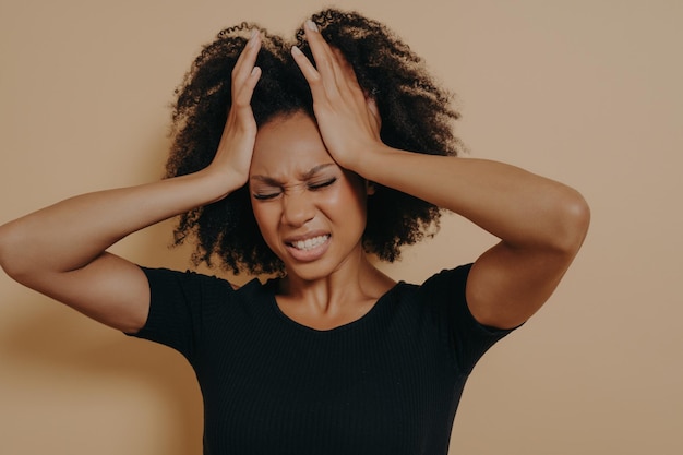 Shocked African American stressed girl holding hands on head and showing despair