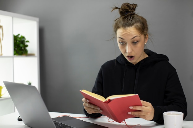 Photo shocked beautiful girl reading book during quarantine. self-education