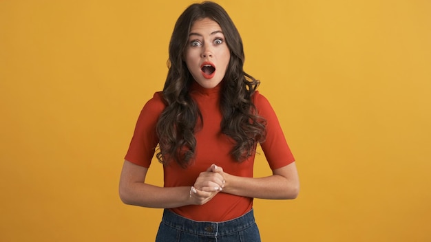 Shocked brunette girl amazedly looking in camera over colorful background Wow expression