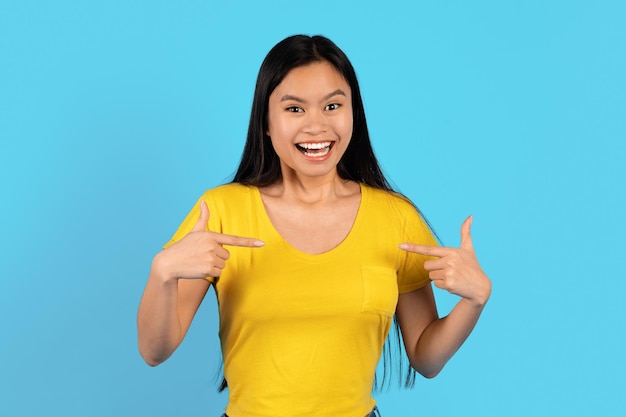 Shocked cheerful inspired young chinese woman in yellow tshirt points fingers at herself