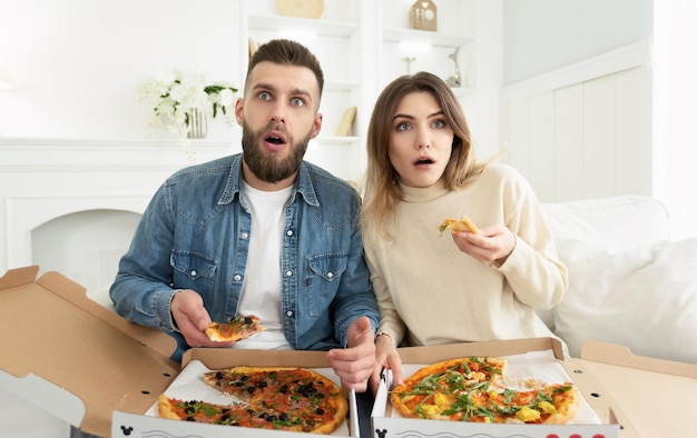 Shocked Couple Watching Film And Eating Pizza