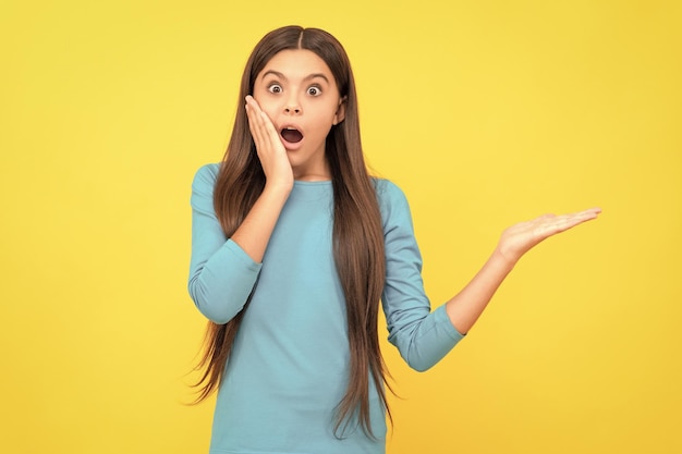 Shocked face portrait of child on yellow background express positive emotions