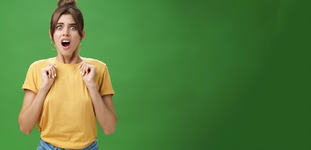 Shocked feminine glamour woman with combed hair in yellow tshirt frowning gasping with opened mouth