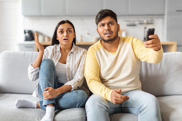 Shocked indian couple reacting to news in bright living room