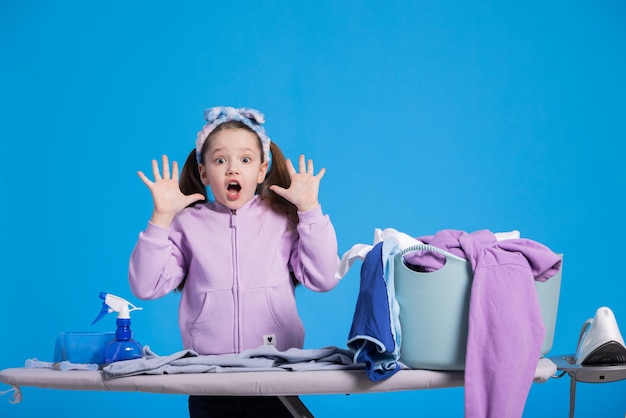 Shocked little sweet girl sees how much ironing awaits her surprised child hands up