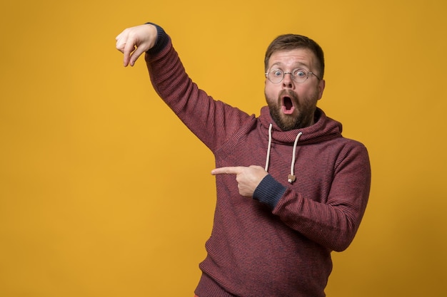 Shocked man showing fingers as if he is holding or picking up an invisible object and points at it with forefinger Copy space