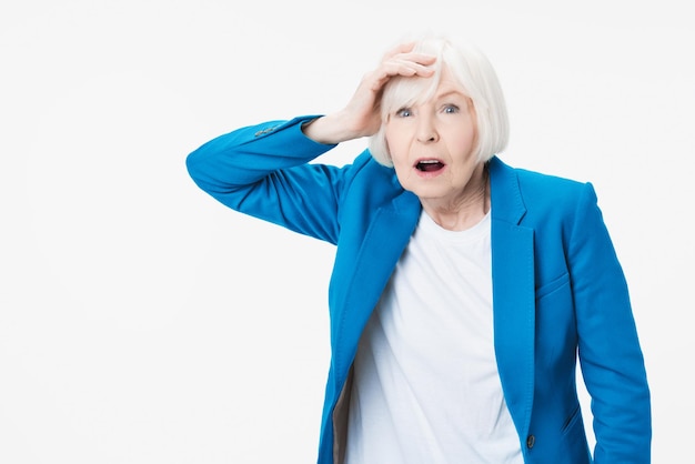 Shocked old mature woman in disbelief isolated on white studio background