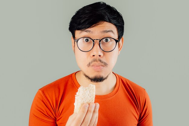 Shocked and surprised Asian man face while eating sandwich.