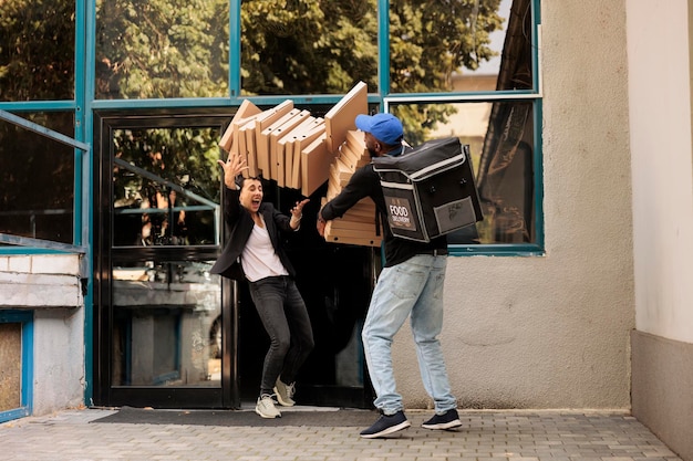 Shocked woman catching falling pizza boxes pile, clumsy pizzeria courier dropping fastfood packages stack at customer in front of office building. Bad food delivery service