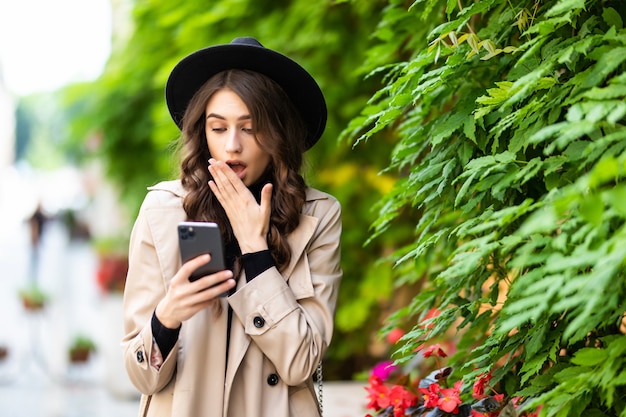 Shocked woman finding surprising news on smart phone in the street