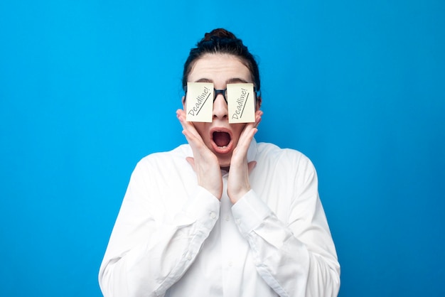 Shocked woman manager screaming in stress on blue background girl office worker with papers