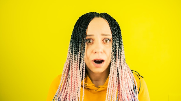 Shocked woman opens mouth in astonishment Surprised young female with goggle eyes looking at camera on yellow background