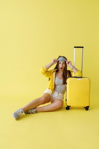 Shocked woman in sleep mask sitting near travel bag