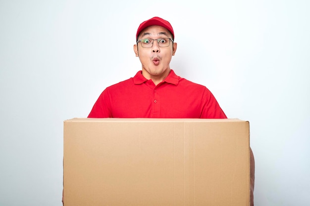 Shocked young asian courier in red uniform and cap look astonished holding client order box