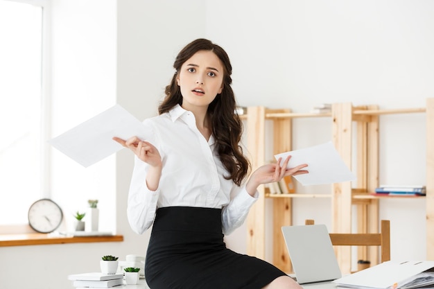 Shocked young business woman surprised by reading unexpected news in document amazed woman office worker feeling stunned baffled by unbelievable information in paper about debt or dismissal