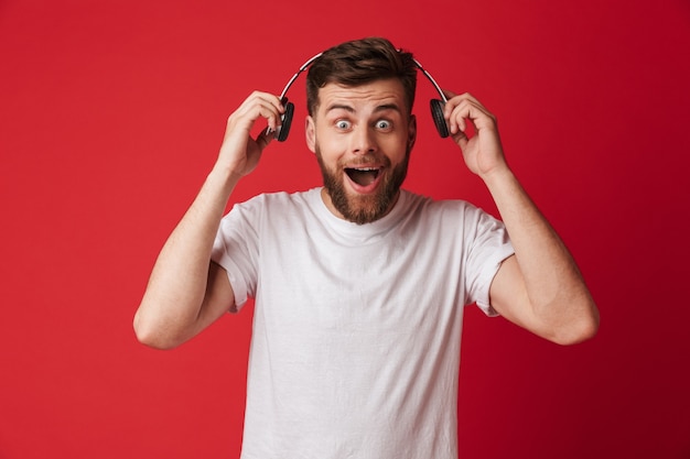 Shocked young man isolated listening music with headphones.