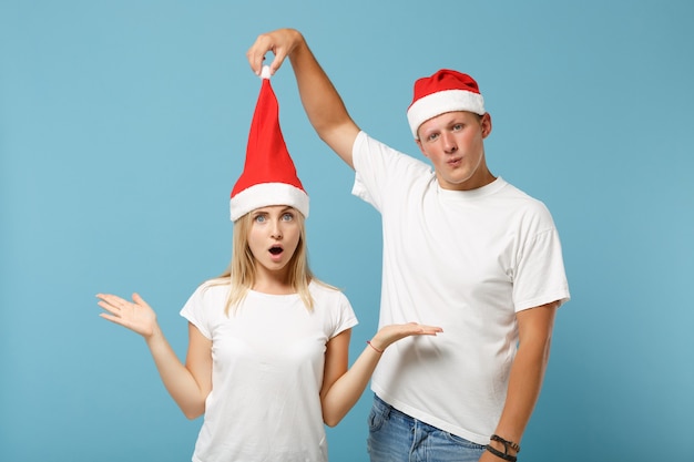 Shocked young Santa couple friends guy and woman in Christmas hat posing 