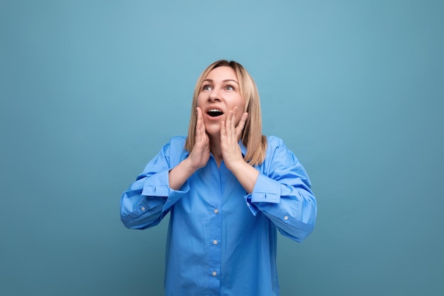 Shocked young woman in casual look grabbing her head on blue background