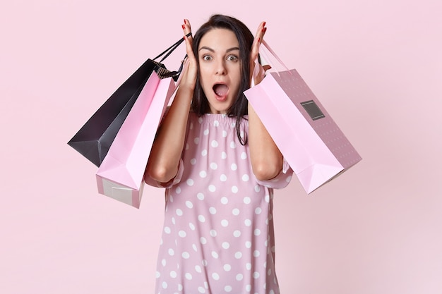 Shocked young woman holding shopping bags