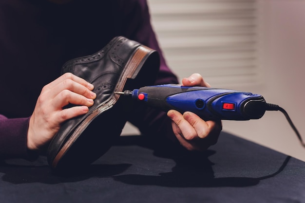 A shoemaker cuts the sole of a Shoe with a shoemaker's automatic cutter