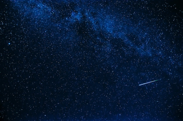 Shooting star in background a starry blue sky at night