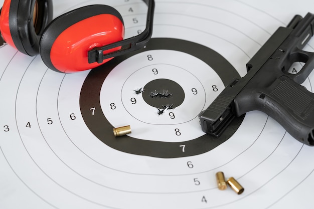 Photo shooting target and bullseye with bullet holes with automatic pistol gun and cartridge bullet.