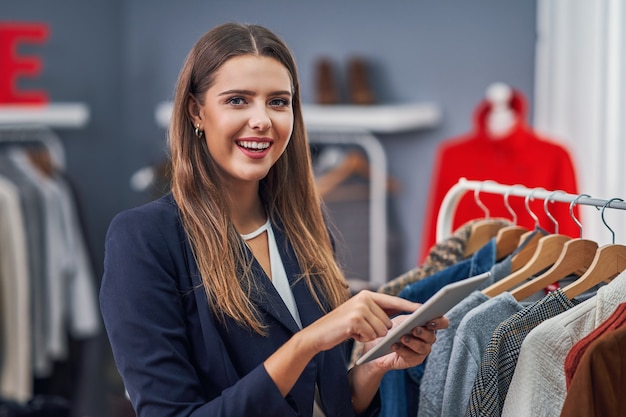 shop assistant in her boutique with winter autumn collection