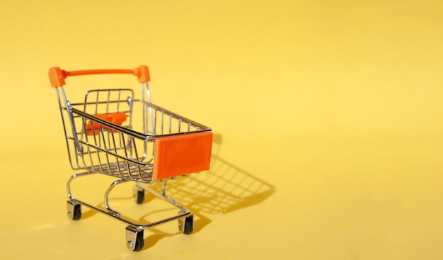 Shopaholic. Buyer. Shopping concept. Close-up. Isolated shopping trolley on a yellow background