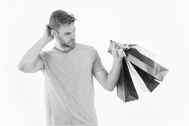 Shopaholic holding colorful paper bags Hipster with stylish bristle isolated on white background Man spending money on presents Fashion addict with puzzled look Christmas shopping sales concept