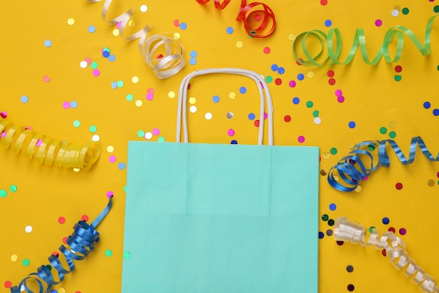 Shopping bag with Colored streamer and confetti on yellow background Shopping day