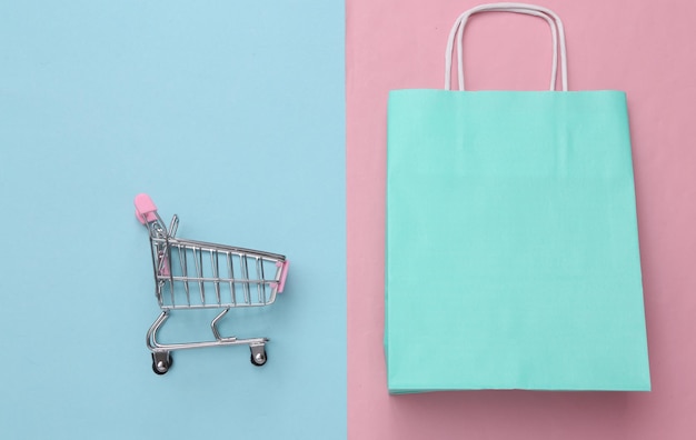 Shopping bag with shopping trolley on pink blue background Sale Top view