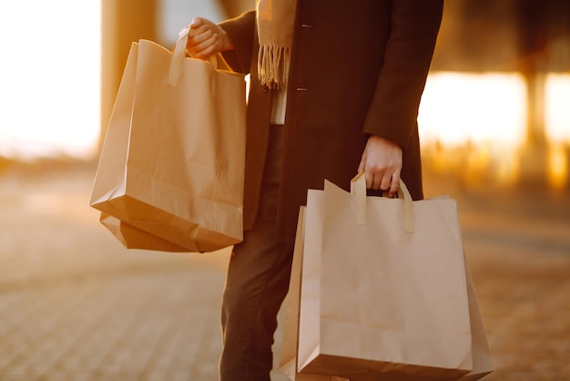 Shopping bags in the hands at sunset Hand of young man with paper bags with purchases