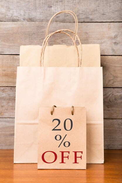 Shopping bags with inscription 20 OFF on wooden background