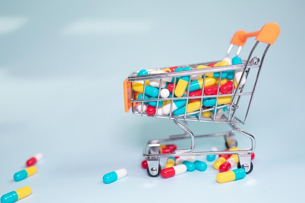 Shopping basket and pills on blue background. The concept of buying drugs online.