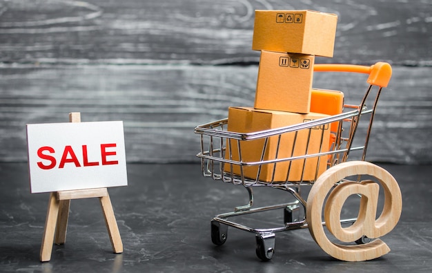 Photo a shopping cart filled with cardboard boxes and an easel with the word sale and email symbol