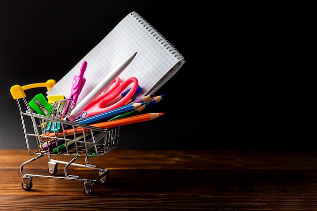 Shopping cart full of stationery or office supplies on dark background