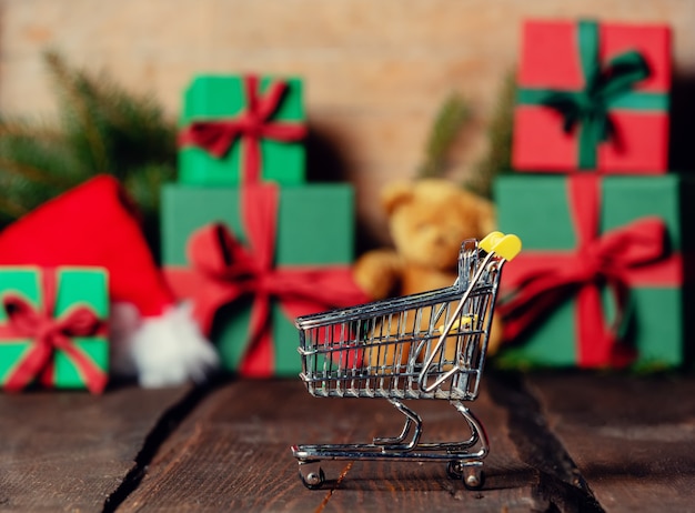 Shopping cart and gifts on wooden table and backgroud.