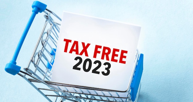 Shopping cart and text tax free 2023 on white paper note list Shopping list concept on blue background